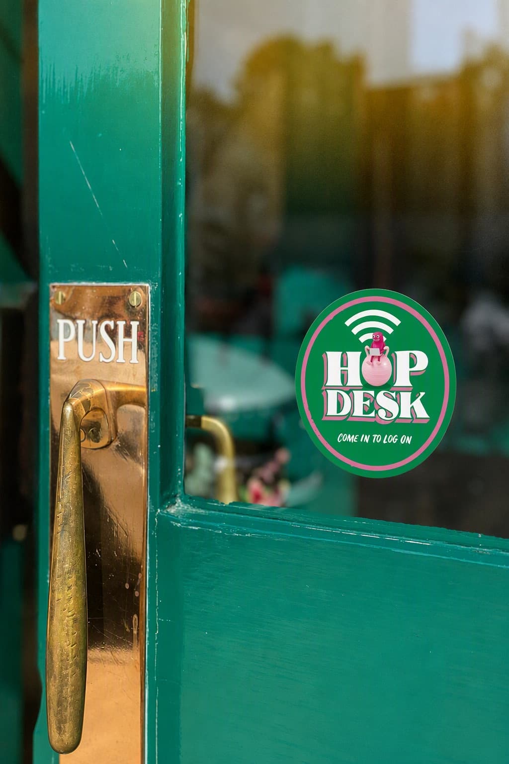A HopDesk sticker on a green pub door reading "come in to log on"
