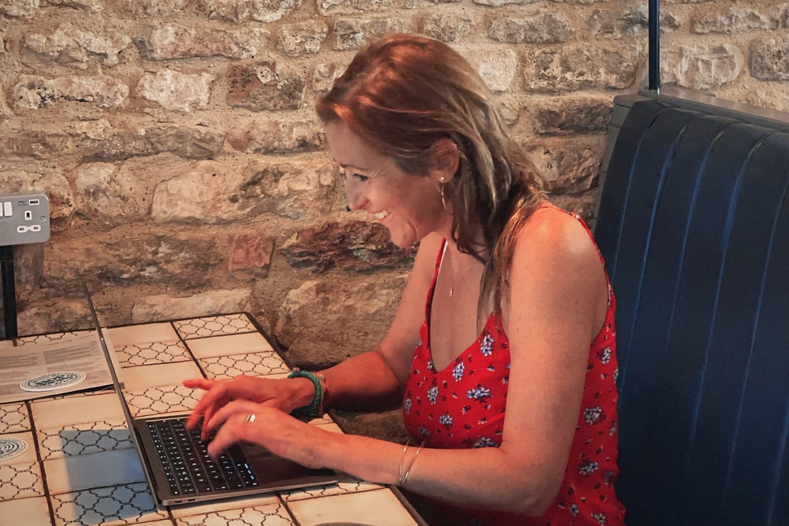 A Hopper working on a laptop at a sunny pub table